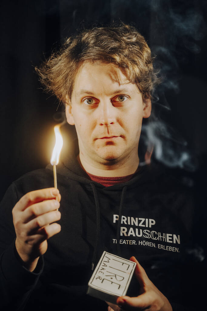 Nico Franke blickt direkt in die Kamera und hält ein soeben angerissenes Streichholz in der Hand.